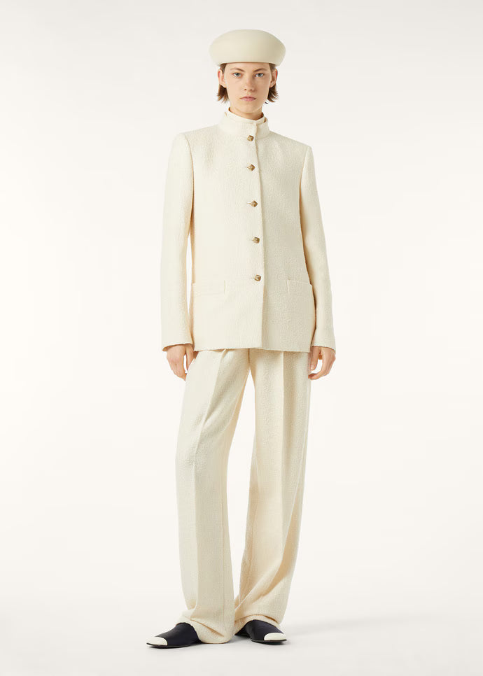 Model wearing a cream structured jacket and wide-leg trousers with a beret